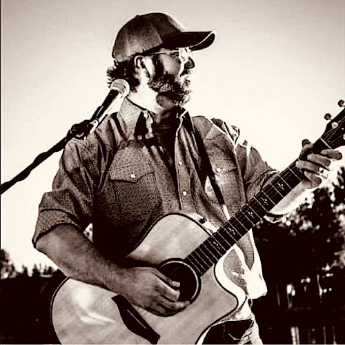 KC Flynn performing acoustic guitar during Beats & Bites Brunch at Riverhouse Lodge in Bend Oregon with guests enjoying brunch.
