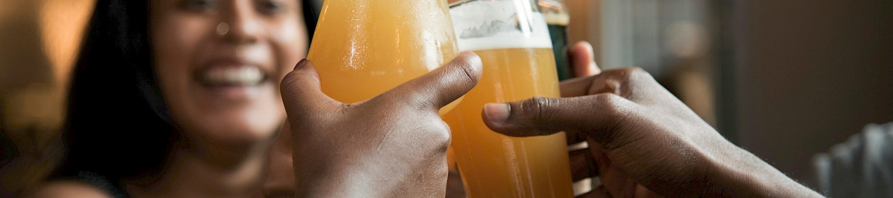 People are toasting with glasses of beer, celebrating together in a lively setting.