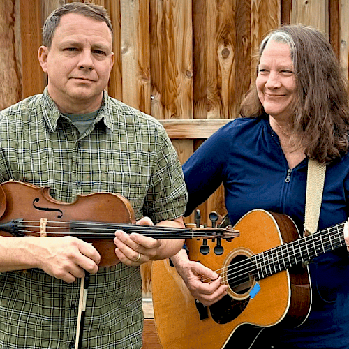 Two people, a man and a woman, are playing musical instruments outdoors in a backyard.