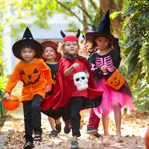 children in halloween costumes running through wooded area