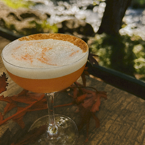 Golden Hour Sour cocktail with maple, bourbon, and cinnamon foam served on the riverside patio at Currents at Riverhouse Lodge in Bend Oregon during golden hour light.