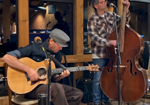 Two folk musicians performing live with acoustic guitar and upright bass during a brunch performance at Currents at Riverhouse Lodge, a riverfront live music venue in Bend, Oregon.