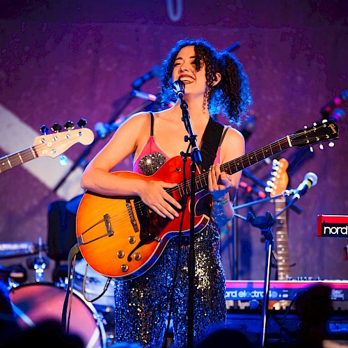 Female singer-songwriter performing live with electric guitar and microphone during Beats & Bites Brunch at Currents at Riverhouse Lodge in Bend, Oregon.