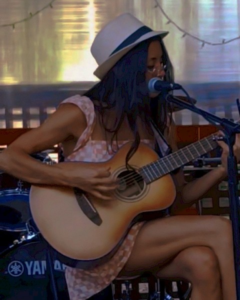 Bre Gonzalez singing and playing acoustic guitar during Beats & Bites Brunch at Riverhouse Lodge Bend Oregon.