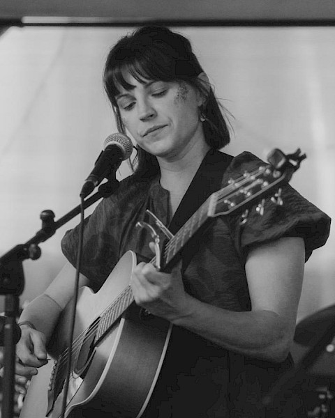 Acoustic folk singer Cecilia Voss performing live guitar music at Currents Restaurant during Live Music Friday at Riverhouse Lodge in Bend Oregon.