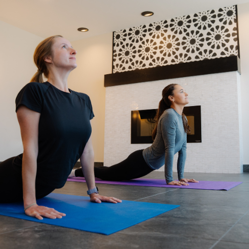 Guests practicing yoga in the peaceful indoor Yoga Zone at Riverhouse Lodge, flowing through poses with a relaxing forest-inspired backdrop.