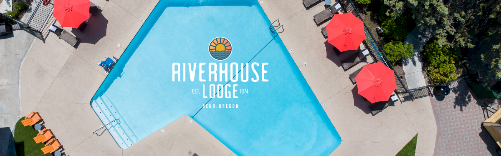 An aerial view of a hotel pool area with red umbrellas, lounge chairs, and the logo 