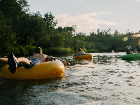 People float down a river on inflatable tubes enjoying a sunny day in nature.