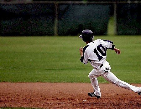 A baseball player wearing a white uniform with the number 10 is running on the field during a game.