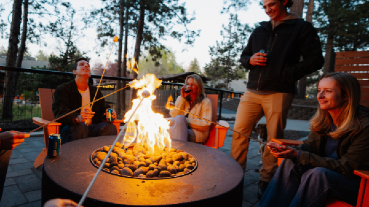 People are enjoying a backyard fire pit gathering, roasting marshmallows and chatting during the evening outdoors.
