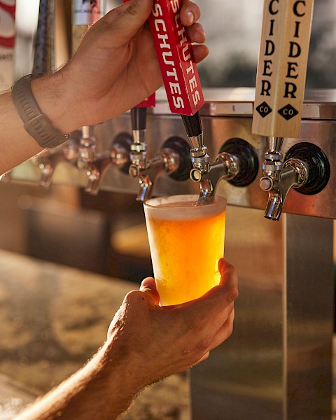 A hand is filling a glass with beer from a tap at a bar or brewery.