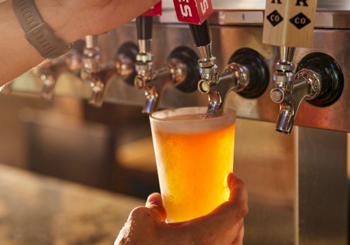 A hand is filling a glass with beer from a tap at a bar or brewery.