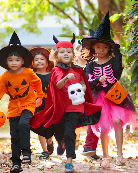 children in halloween costumes running through wooded area