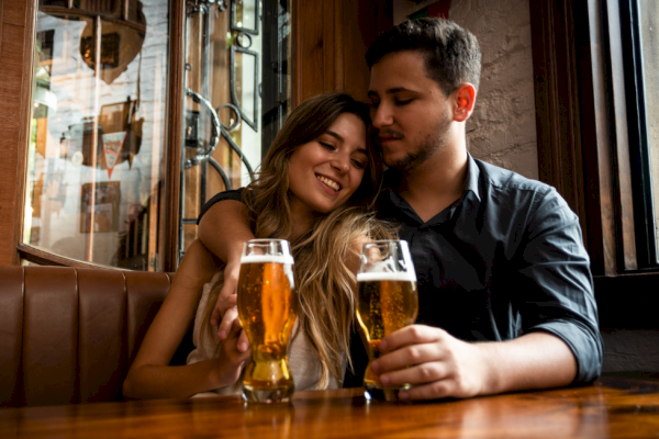 A couple shares a happy moment with drinks in a cozy, warmly-lit pub.