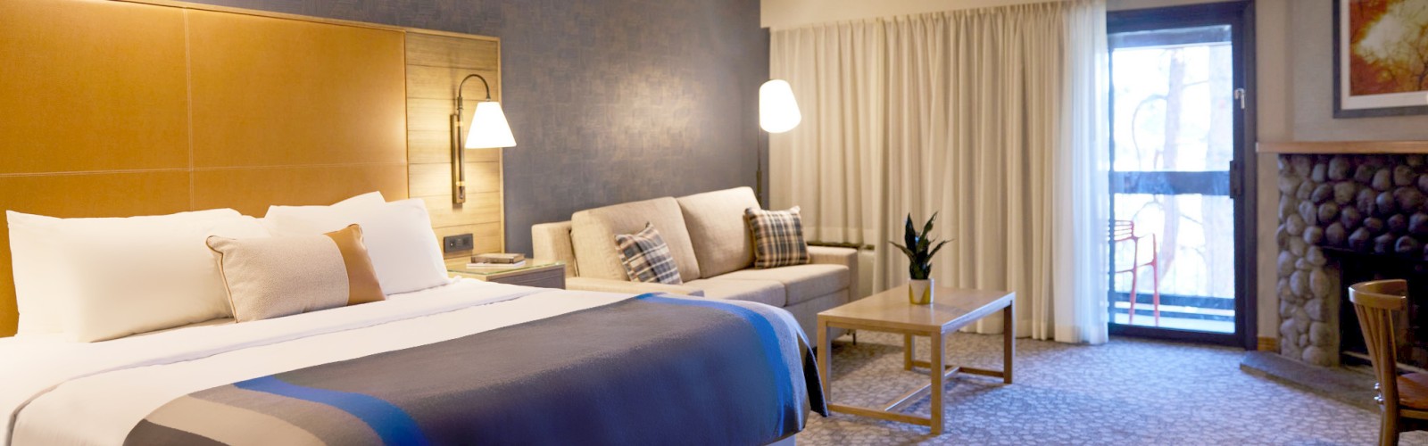 A well-appointed hotel room at Riverhouse Lodge located in Bend, Oregon with a King bed, nightstands, lamps, a desk, chair, and artwork at Riverhouse on the Deschutes in Bend, Oregon.