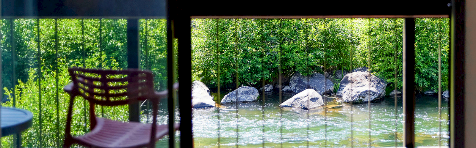 View of the Deschutes River through a window, with a chair and table in a serene setting.