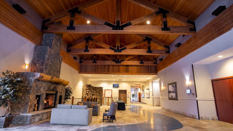 A cozy, modern lobby area with wooden beams, a stone fireplace, seating, and artwork on the walls.