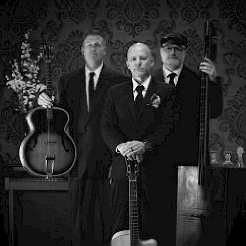 A black and white photo featuring three men in suits holding musical instruments against a vintage patterned backdrop.