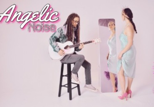 A person with dreadlocks plays guitar on a stool, while a woman in a blue dress and pink heels stands by a mirror. Text reads 