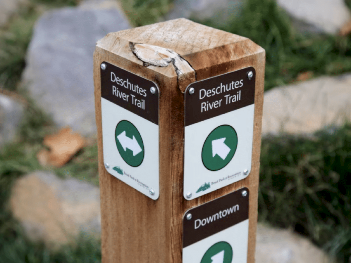 The image shows a wooden trail sign for 