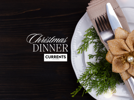 A festive table setting with a plate, cutlery wrapped in a napkin, a gold flower, and greenery. Text reads 