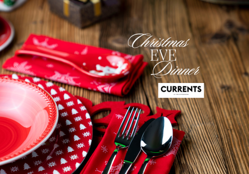 A festive table setting with red plates and cutlery on a wooden table is shown. Text reads 