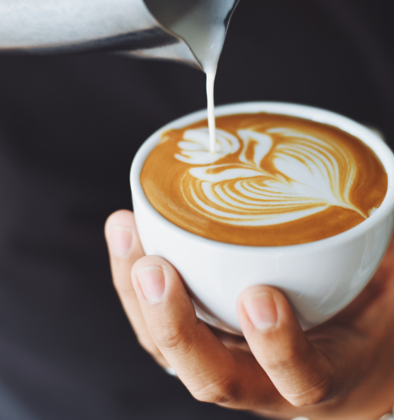 Barista pours milk to create latte art flower at Riverhouse Lodge's coffee bar, open daily in Bend, Oregon from 6am to 11am