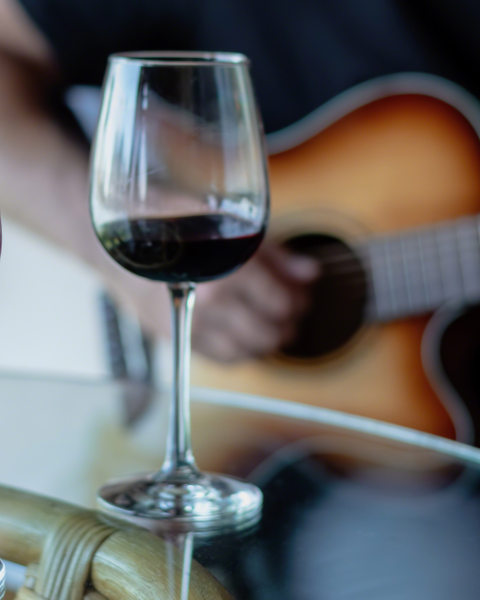 Acoustic live music with two glasses of red wine on a riverside patio table at Currents at Riverhouse Lodge in Bend, Oregon