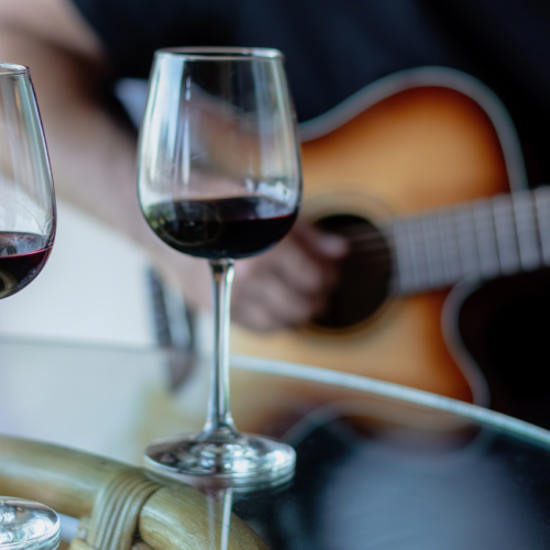 Acoustic live music with two glasses of red wine on a riverside patio table at Currents at Riverhouse Lodge in Bend, Oregon