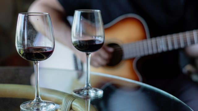 Acoustic live music with two glasses of red wine on a riverside patio table at Currents at Riverhouse Lodge in Bend, Oregon