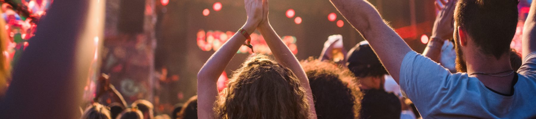 A crowd enjoying a lively concert at the 2025 Kendall Toyota of Bend FREE Summer Concert Series at the Deschutes County Fair & Rodeo, with people raising their hands and vibrant stage lights illuminating the scene.