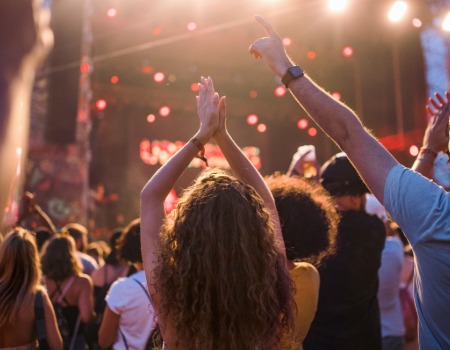 A crowd enjoying a lively concert at the 2025 Kendall Toyota of Bend FREE Summer Concert Series at the Deschutes County Fair & Rodeo, with people raising their hands and vibrant stage lights illuminating the scene.