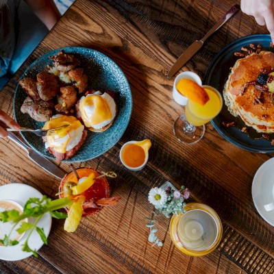 Guests enjoy a hearty brunch with eggs Benedict, pancakes, lattes, and cocktails at Currents at Riverhouse Lodge in Bend, Oregon—perfect for a flavorful staycation escape