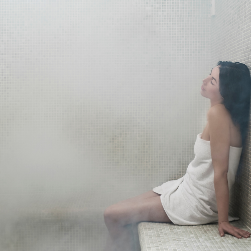 Guest wrapped in a towel inside the mist-filled steam room at Riverhouse Lodge—an ideal way to relax and recharge in Central Oregon.