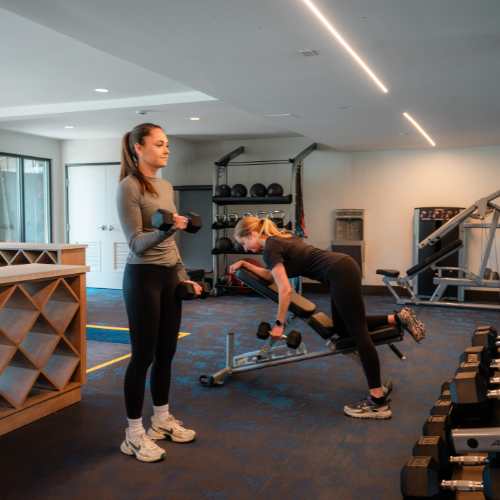 Two guests using free weights and strength machines in the fitness center at Riverhouse Lodge—well-equipped for your fitness-focused getaway.