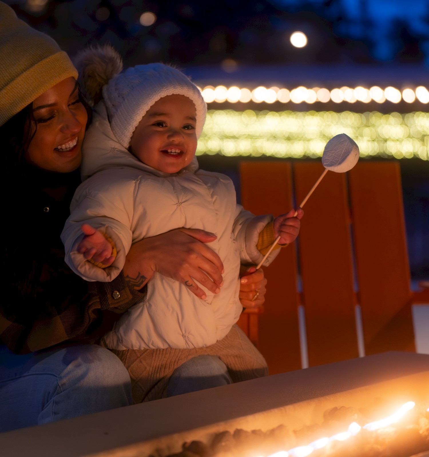 Family enjoying outdoor firepit at Riverhouse Lodge Bend Oregon in winter with holiday lights and snow, cozy dog-friendly hotel for après ski and riverfront stays.
