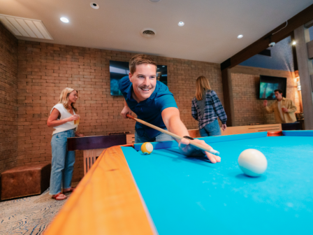 People are playing complimentary pool at Currents Lounge at Riverhouse Lodge in Bend, Oregon, with others socializing in the background.