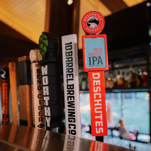 A variety of beer tap handles, including one for Deschutes Fresh Squeezed IPA, is displayed in Currents at Riverhouse in Bend, Oregon with $5 beer specials on Sundays for NFL
