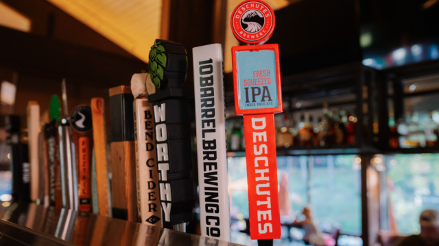 A variety of beer tap handles, including one for Deschutes Fresh Squeezed IPA, is displayed in Currents at Riverhouse in Bend, Oregon with $5 beer specials on Sundays for NFL