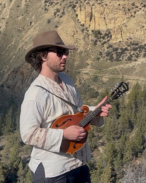 Garrett Leon live music at Currents Riverhouse Lodge in Bend Oregon on October 3 2025, performing outdoors with mandolin against a mountain backdrop