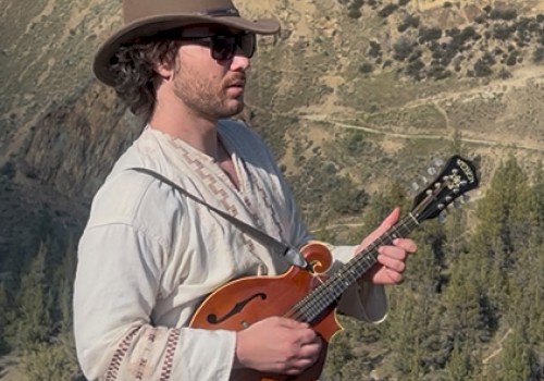 Garrett Leon live music at Currents Riverhouse Lodge in Bend Oregon on October 3 2025, performing outdoors with mandolin against a mountain backdrop