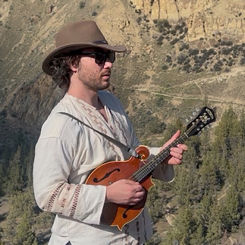 Garrett Leon live music at Currents Riverhouse Lodge in Bend Oregon on October 3 2025, performing outdoors with mandolin against a mountain backdrop