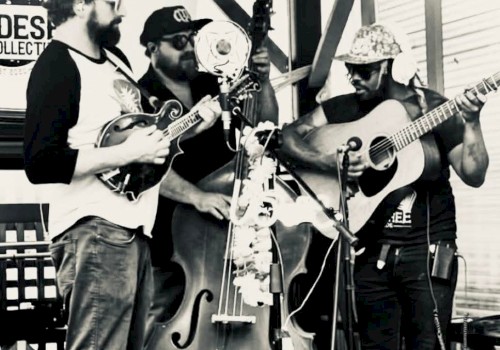 A black and white image of three musicians playing a banjo, double bass, and guitar, performing together outdoors.