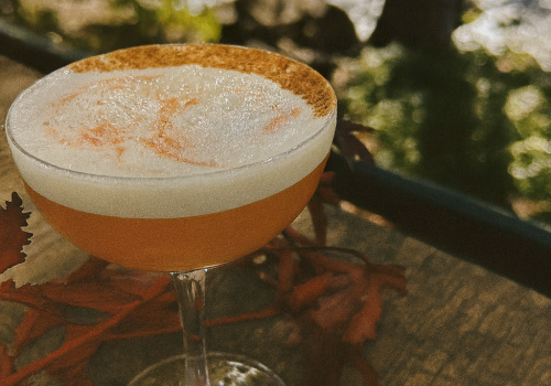 Golden Hour Sour cocktail with maple, bourbon, and cinnamon foam served on the riverside patio at Currents at Riverhouse Lodge in Bend Oregon during golden hour light.