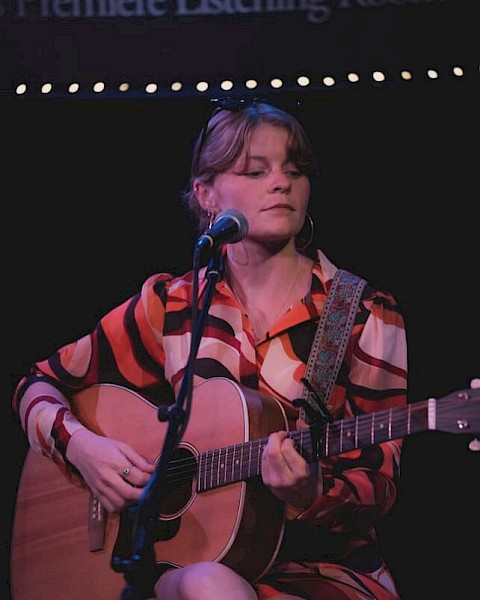 Indie folk musician Aslin performs live on stage, singing and playing acoustic guitar, featured live music artist at Currents at the Riverhouse in Bend, Oregon.