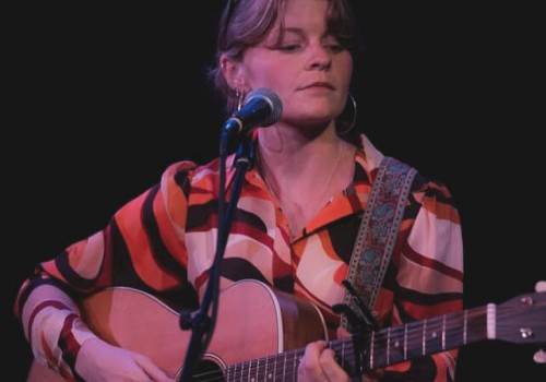Indie folk musician Aslin performs live on stage, singing and playing acoustic guitar, featured live music artist at Currents at the Riverhouse in Bend, Oregon.