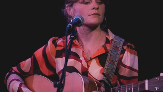 Indie folk musician Aslin performs live on stage, singing and playing acoustic guitar, featured live music artist at Currents at the Riverhouse in Bend, Oregon.