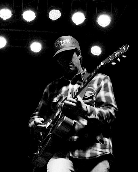 Black-and-white photo of guitarist Mark Ransom performing live on stage, playing electric guitar at Currents at the Riverhouse in Bend, Oregon.
