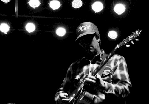 Black-and-white photo of guitarist Mark Ransom performing live on stage, playing electric guitar at Currents at the Riverhouse in Bend, Oregon.